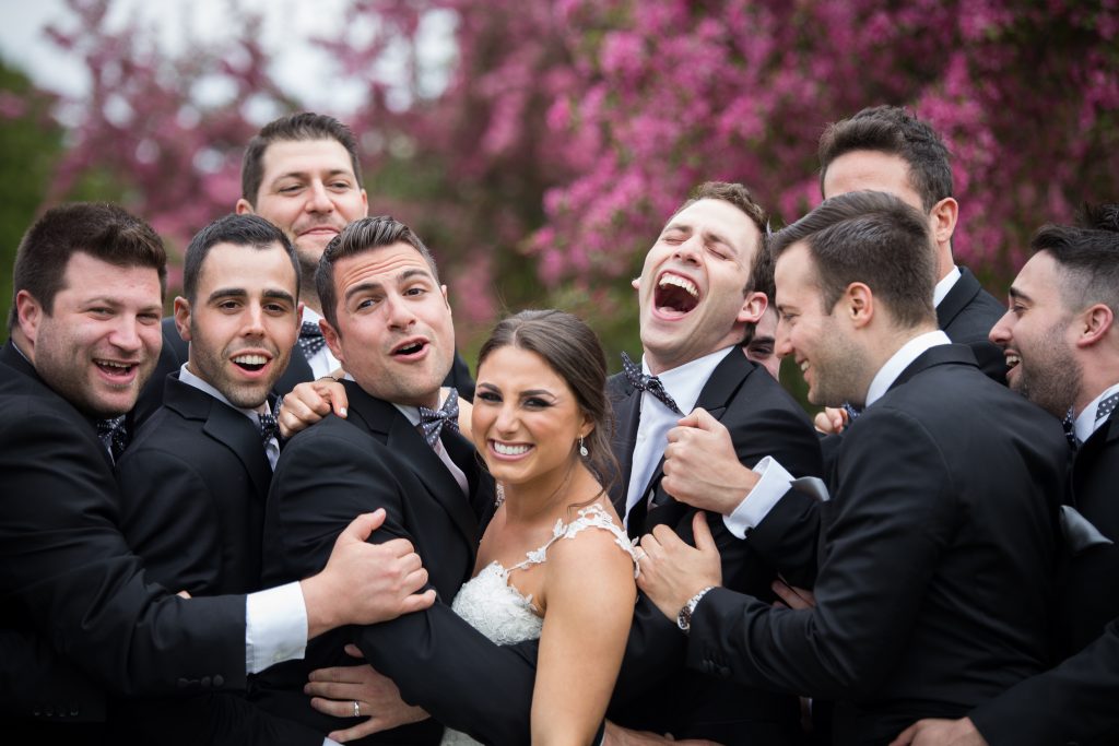 Bride surrounded by groomsmen outside on her wedding day