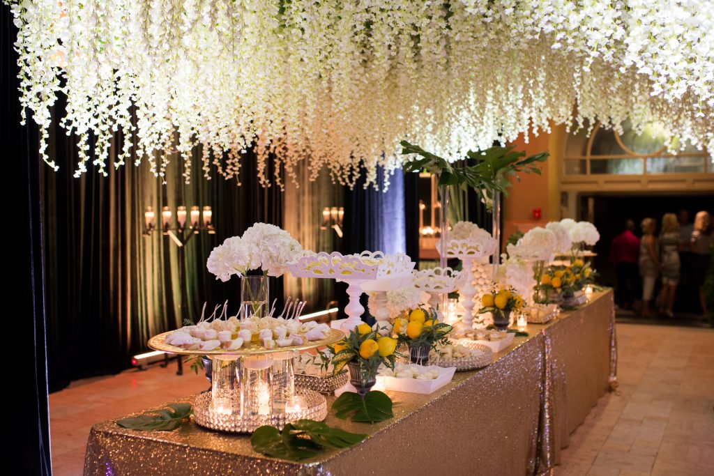 Sweet table under cascading white flowers from the ceiling with gold table cloth