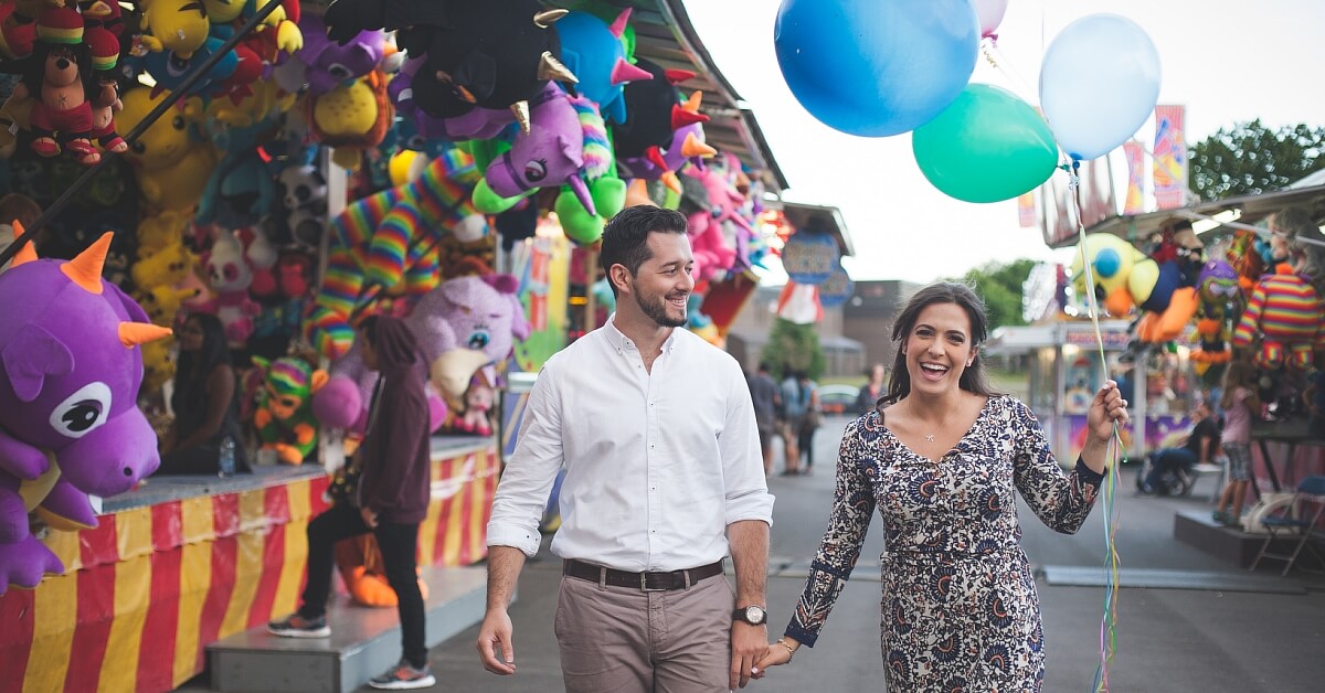 A couple holding balloons at a carnival